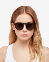 Lentes de sol Hawkers unisex, modelo Warwick Raw, con montura redonda color negro mate y lentes polarizadas color gris oscuro. Fabricados en España.