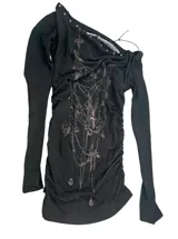 Remera manga larga de corte slim fit en color negro, confeccionada en poliéster con estampado por sublimación en el frente. Presenta escote redondo amplio con detalle drapeado y tachas metálicas aplicadas en el borde.