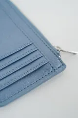 Billetera pequeña color negro con cierre de cremallera plateado y apliques de tachas metálicas redondas en la parte frontal.