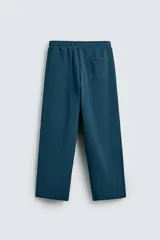 Pantalón jogger de corte relajado y pernera ancha, confeccionado en tejido de algodón con interior perchado. Presenta cintura elástica con cordón interior, bolsillos laterales y un bolsillo trasero de plastrón.