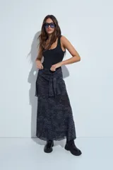 Falda larga de corte fluido con estampado de cuadros en tonos oscuros, rojizos y blancos. Presenta un diseño ligero con terminaciones onduladas en el ruedo.