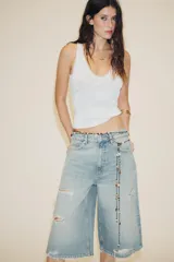 Collar largo de cordón negro ajustable, adornado con múltiples cuentas de piedra en tonos marrones, beige y blanco, y varios dijes metálicos dorados y plateados, incluyendo una concha marina y formas orgánicas.