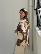 Sweater de punto con estampado animal print tipo vaca en tonos camel y marrón, de corte holgado, escote en V y mangas tres cuartos con dobladillo.