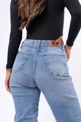 Jean corte mom de tiro alto, color azul claro con lavado clásico. Presenta cierre frontal con botón y cinco bolsillos tradicionales.