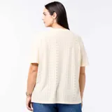 Camiseta de manga corta y cuello en V, confeccionada en tejido de punto calado con sutiles perforaciones geométricas, de corte holgado y diseño versátil.