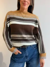 Sweater tejido de punto con diseño de rayas horizontales en tonos tierra, marrones y blanco. Presenta cuello redondo, corte holgado con mangas tipo murciélago y puños y pretina acanalados.