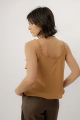 Musculosa negra con escote en V, breteles finos regulables y doble volado frontal con pespuntes.