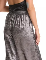 Pantalón wide leg de tela laminada metalizada color blanco, con pretina elástica y lazo de ajuste en la cintura. Cuenta con bolsillos laterales.