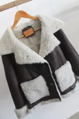 Campera estilo aviador de cuero genuino color marrón, con forro, solapas, puños, bolsillos frontales aplicados y bordes de corderito sintético en tono tostado. Cuenta con cierre frontal de botones.