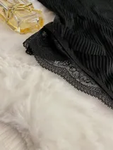 Body negro de terciopelo acanalado con detalles de microtul y encaje, cuello alto y espalda descubierta.