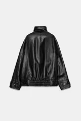 Chaqueta de corte oversize con acabado efecto piel. Presenta cuello alto, cierre frontal con cremallera y botones ocultos bajo solapa, bolsillos de plastrón con solapa en el delantero, mangas largas ajustables con trabillas y bajo ajustable con hebillas metálicas.