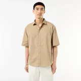 Camisa de manga corta de popelín color beige, con cuello clásico y cierre frontal de botones.