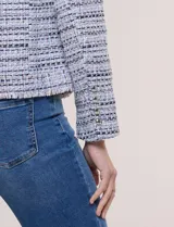 Chaqueta corta estructurada confeccionada en tejido texturado boucle estilo tweed en tonos azul, blanco y negro. Cuenta con forro interno, cuello camisero, frente abierto con bordes deshilachados, bolsillos tipo plaque al frente con botones metálicos y mangas largas.