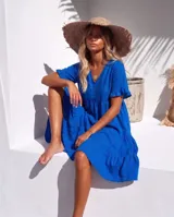 Vestido corto color azul de lino, con escote en V, mangas cortas con volados y diseño escalonado en la falda.
