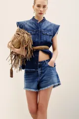 Short de denim azul medio con diseño de cinco bolsillos, cierre frontal con botones y bordes desmechados en el ruedo.
