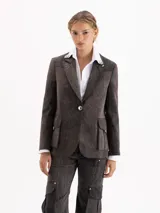 Blazer de gabardina con efecto desgastado, con detalles en cuero vacuno en las solapas. Presenta bolsillos plaqué con tapa, cierre frontal con botón forrado y canesú marcado en el delantero.