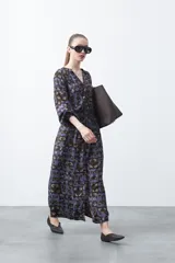 Vestido largo de silueta fluida con estampado abstracto en tonos azul, marrón y beige. Presenta escote en V con botones forrados y cintura elastizada. Mangas 3/4 abullonadas.