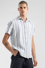 Camisa de manga corta con rayas verticales en tonos azul, gris y blanco. Tiene cuello clásico, botones de coco y un bolsillo en el pecho.