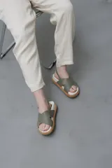Sandalias bajas color verde oliva, con dos tiras anchas cruzadas sobre el empeine y tira trasera con hebilla.