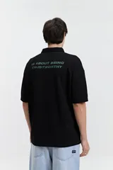 Remera polo color crema con logo bordado en el pecho, de corte amplio y mangas cortas.