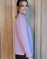 Camisa de manga larga con estampado de rayas verticales en tonos crudo y beige. Presenta cuello alto con volados, cierre frontal con botones dobles y puños con volados.