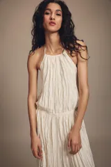 Vestido largo de cuello halter con diseño plisado y textura arrugada. Presenta espalda descubierta con cierre de lazo y cintura elástica.