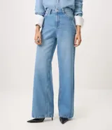 Pantalón wide leg de tiro alto confeccionado en jean de algodón, con pretina con pasacintos, cierre frontal con botón y cremallera, y bolsillos delanteros y traseros.