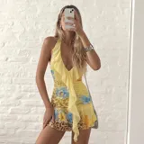 Vestido corto amarillo con estampado floral y animal print, escote halter pronunciado y volados en cascada al frente.