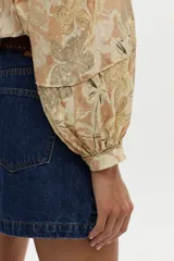 Blusa estampada con diseño paisley en tonos beige y amarillo, con mangas abullonadas de tres cuartos y escote en V profundo.
