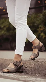 Sandalia de cuero color taupe con taco ancho y hebilla lateral redonda.