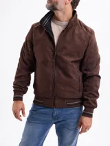 Campera reversible de estilo bomber, confeccionada en material tipo gamuza color marrón de un lado y tejido técnico negro del otro. Presenta cierre frontal, bolsillos laterales con cierre y puños y ruedo acanalados con detalles de líneas horizontales.