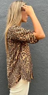 Camisa de manga corta con estampado animal print, cuello clásico y cierre frontal con botones. Presenta un corte holgado y fluido.