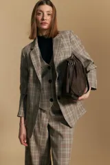 Blazer de corte sastrero con estampado de cuadros en tonos beige, marrones y rojizos. Presenta solapas clásicas, cierre frontal con un botón y bolsillos laterales con solapa.