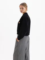 Buzo negro de corte regular, confeccionado en rústico de algodón con cuello redondo, puños y cintura en ribb. Presenta una estampa frontal de un corazón con diseño de animal print atravesado por una flecha.