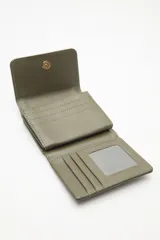 Billetera compacta de cuero sintético negro, con solapa que combina texturas lisas y efecto reptil. Incluye un aplique metálico circular con logo grabado en el frente y cierre con broche.