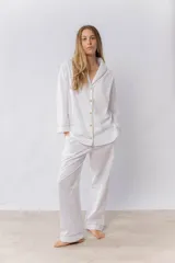 Pijama de dos piezas confeccionado en popelina de algodón. Incluye una camisa de manga larga con cuello smoking, cierre frontal abotonado y detalles de vivo en contraste en cuello, puños y solapas. El pantalón cuenta con cintura elástica, bolsillos laterales y detalles de vivo en los bajos.