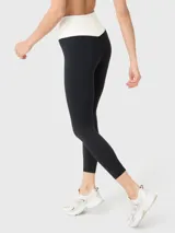 Calza deportiva de tiro alto con diseño bicolor, presentando una cintura en forma de V en color blanco y el resto de la prenda en negro. Confeccionada en tejido suave y elástico con ajuste ergonómico.