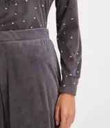 Pijama largo de plush gris con estampado de lunares blancos y corazones rojos. Incluye una blusa de manga larga con cuello redondo y un pantalón con puños ajustados.