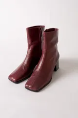 Bota de caña media con textura de reptil en color negro, punta cuadrada y taco bloque.