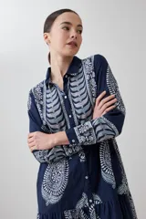 Maxi vestido azul marino con estampado de arabescos en blanco, corte camisero, cuello clásico, mangas 3/4 y falda escalonada.