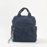 Mochila de diseño acolchado con patrón geométrico en relieve, color azul marino. Cuenta con doble asa superior, bolsillo frontal con cierre, compartimentos laterales y un colgante decorativo de cordón con cuentas de colores en el tirador del cierre.