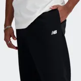 Pantalón tipo jogger New Balance de corte holgado, color negro, con cintura elástica y cordón de ajuste interno. Presenta bolsillos laterales y bolsillo posterior con cierre, además de puños elásticos en los tobillos y logo de la marca bordado en la pierna.