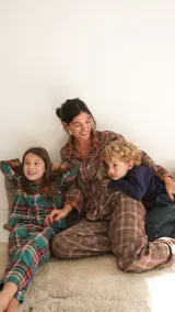 Conjunto de pijama a cuadros con ribetes en color lila, compuesto por camisa de manga larga con botones y pantalón largo.