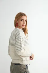 Campera tejida de punto con cierre frontal, diseño a rayas horizontales en tonos gris y blanco, cuello redondo y bolsillos frontales tipo parche.
