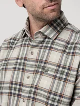 Camisa de manga larga con estampado de cuadros en tonos beige, verde y naranja. Presenta cuello clásico, cierre frontal con botones y un bolsillo en el pecho con el logo de la marca bordado.