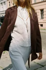 Chaqueta marrón de efecto ante con cuello solapa, manga larga, bolsillos delanteros de plastrón, cierre frontal con botones y cinturón a juego.