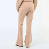 Pantalón de felpa ligera en color beige, con corte bootcut y costura central vertical en el frente de cada pierna.
