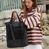 Bolso tote negro con bolsillo frontal con cierre y asas de mano y hombro.