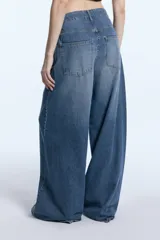 Jean de tiro medio con corte wide leg, confeccionado en denim de algodón con lavado localizado y efecto de bigotes. Presenta cierre frontal con botón y bolsillos laterales y traseros.