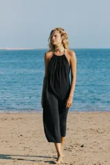 Vestido midi negro con cuello halter, lazada ajustable en el cuello y diseño fluido con espalda descubierta.